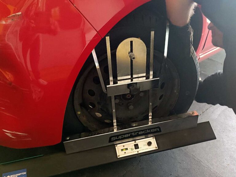 Tyre technician from Bedhampton Tyres is using a supertraker wheel tracking tool on the wheel of a car in the workshop