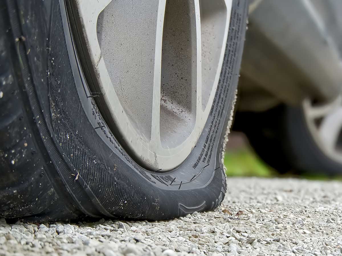enlarged image showing a flat tyre on a car parked in a driveway